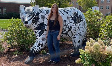 萨姆·库什曼站在她用当地植物的形象画的熊雕像前.