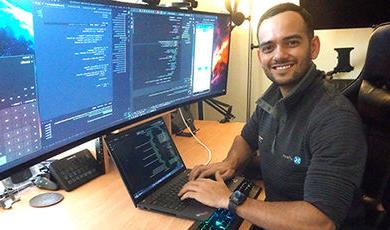 Brenner Campos works at a desk with multiple computer monitors.