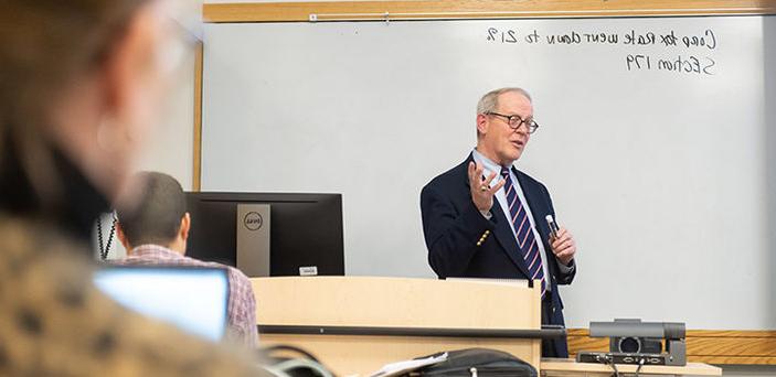 Professor Mark Crowley teaching in front of a white board with notes on the corporate tax rate